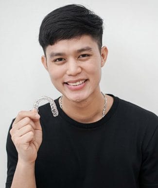young man holding an Invisalign tray 