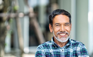 an older man smiling while standing outside