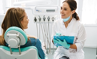 Dentist smiling while taking notes on clipboard