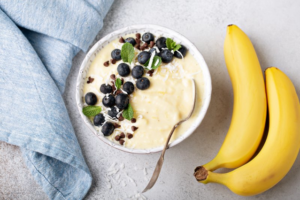 Bowl of yogurt with berries and two bananas on carpet background